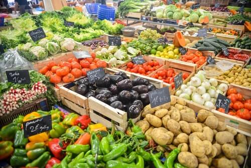 A large number of crates holding a variety of produce is pictured. Green and red pepper, eggplants, tomatoes, potatoes, onions, cauliflower and lettuce are the majority of items portrayed. All of the produce portrayed play an important part in Canadian's health according to Canada's Food Guide.