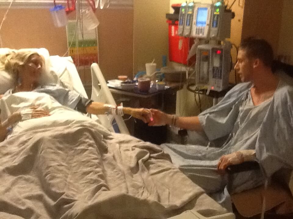 Liz in a hospital bed with son holding her hand