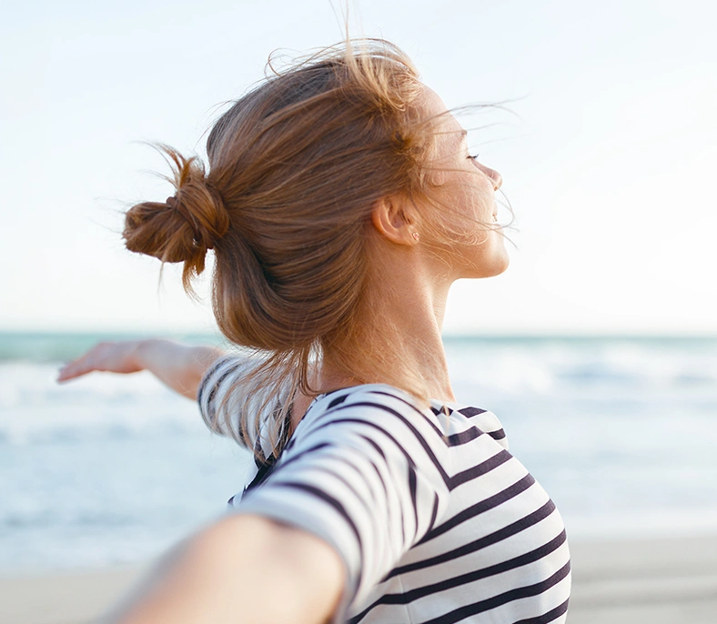 Happy woman on the beach with her arms spread wide