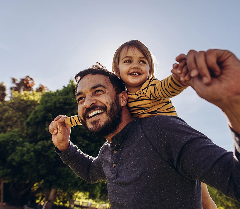 A young child and his father playing outside on a sunny day