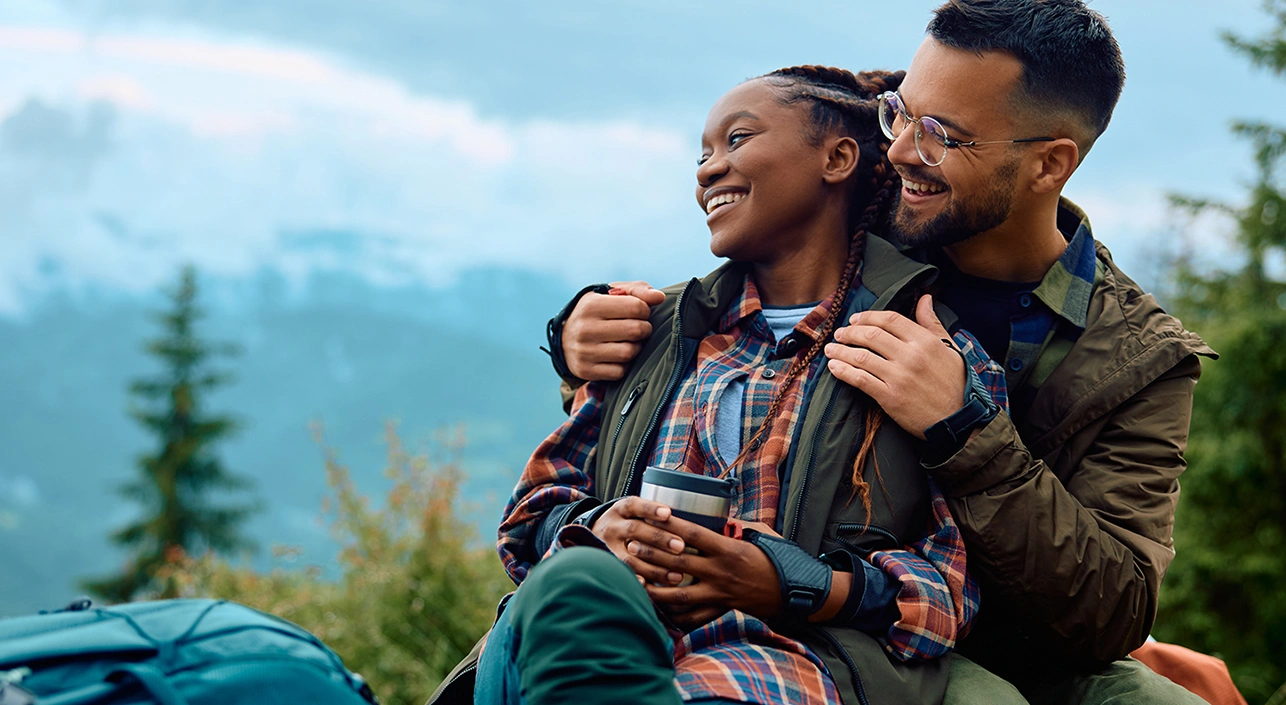 Man and woman hugging while taking a break on a hike